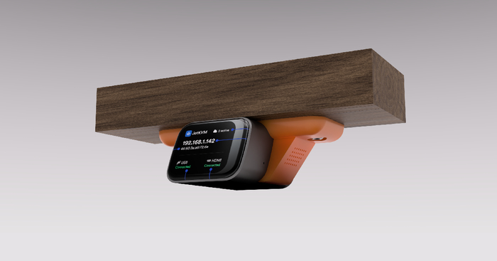 A protective sleeve that mounts a JetKVM underneath a desk.